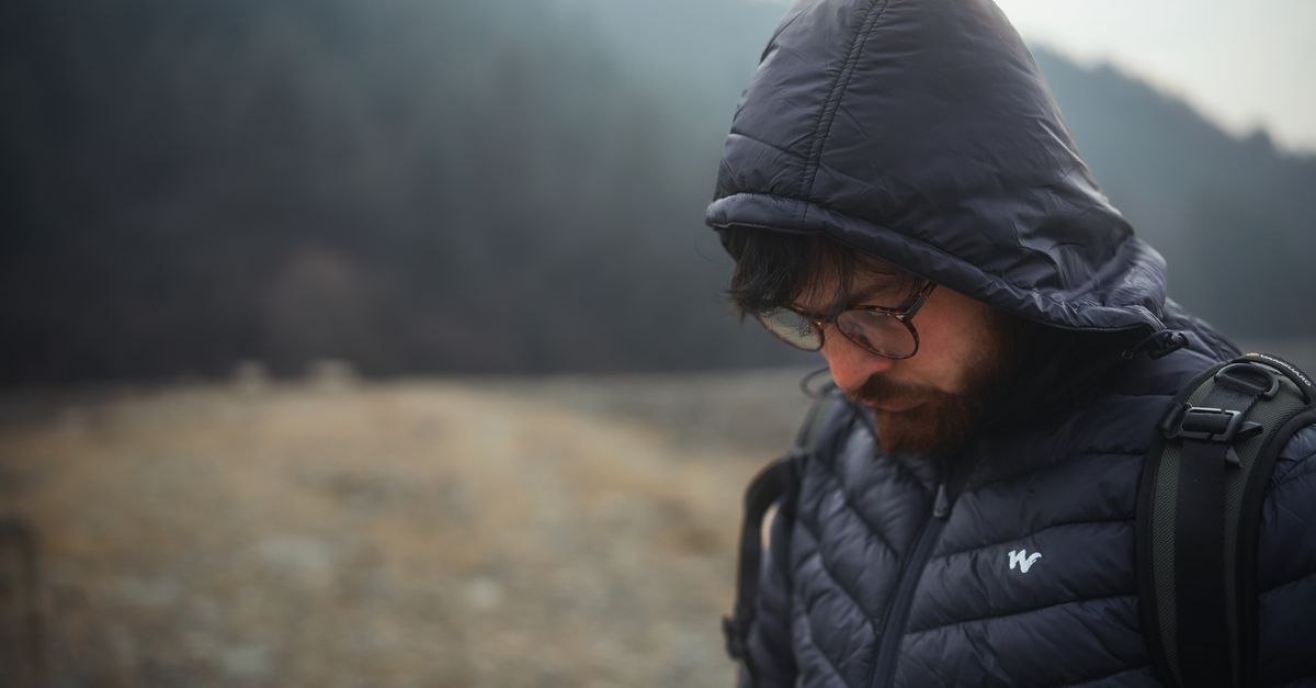 Doudoune outdoor portée en montagne face à un ciel dégagé en hiver