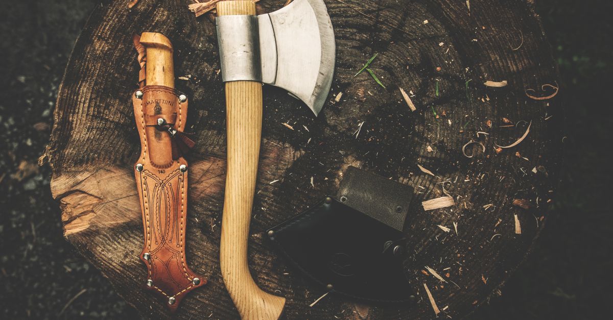 Outils bushcraft couteau et hache posés sur une souche en forêt