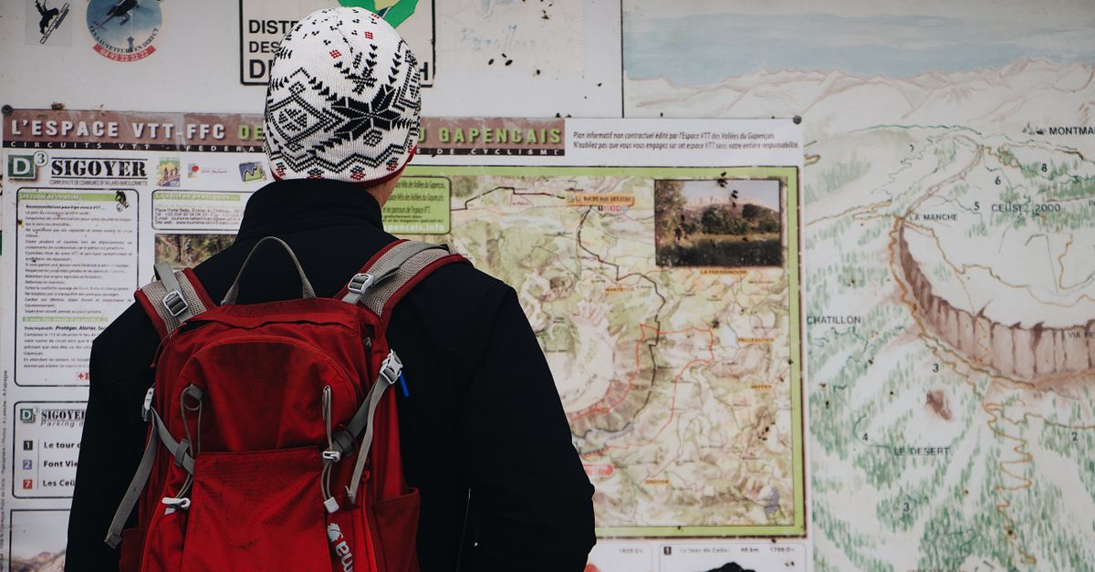 Hiker studying a topographic map before heading into survival mode in a forest