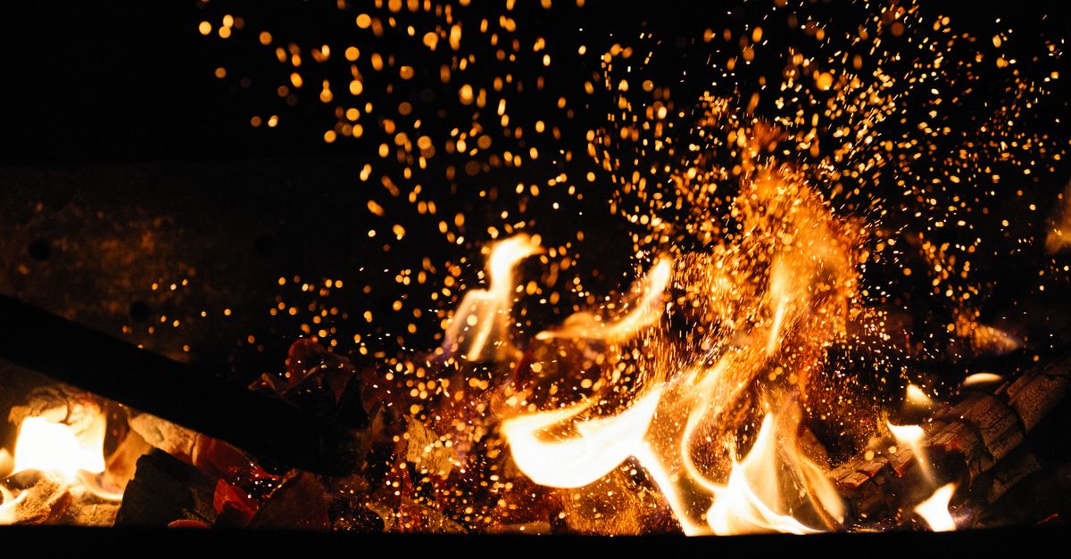 Survival fire starter throwing sparks from ferrocerium onto wood