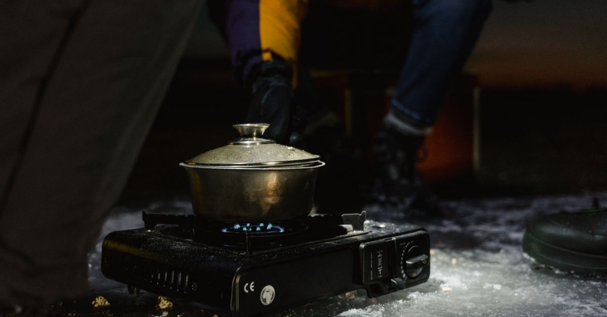 Pot of snow melting on a stove in the mountains