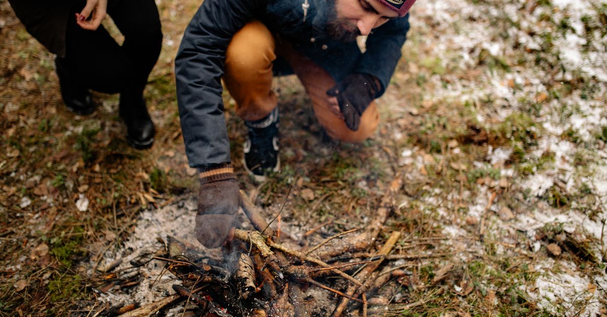 Faire du feu par friction, mains actionnant un archet à feu sur du bois