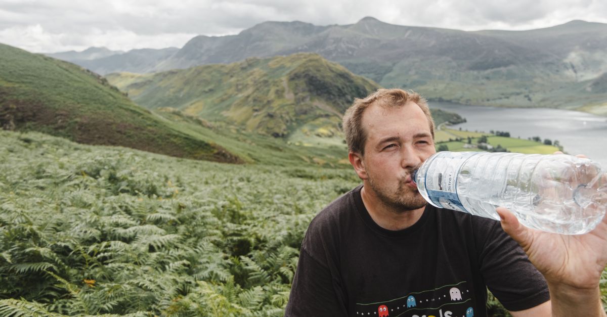 Portable water filter, hiker drinking water outdoors in nature