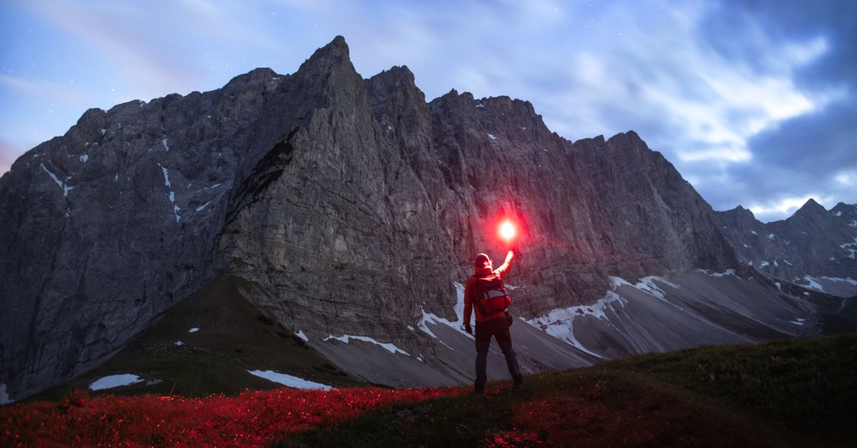 Signaler sa position sans réseau, randonneur agitant une fusée de détresse en montagne