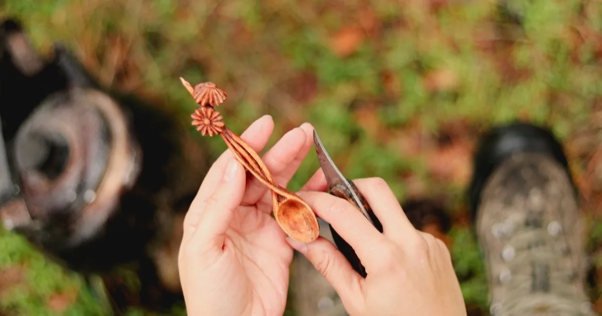 Cuillère en bois taillée au couteau, tenue entre les mains en forêt