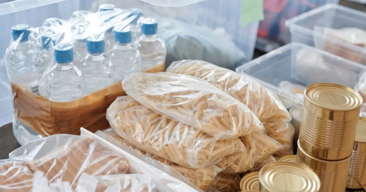 Réserve d'eau d'urgence en bouteilles rangée avec pâtes et conserves
