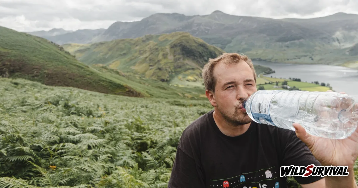 How much water to carry: a hiker drinking from a bottle above a mountain lake