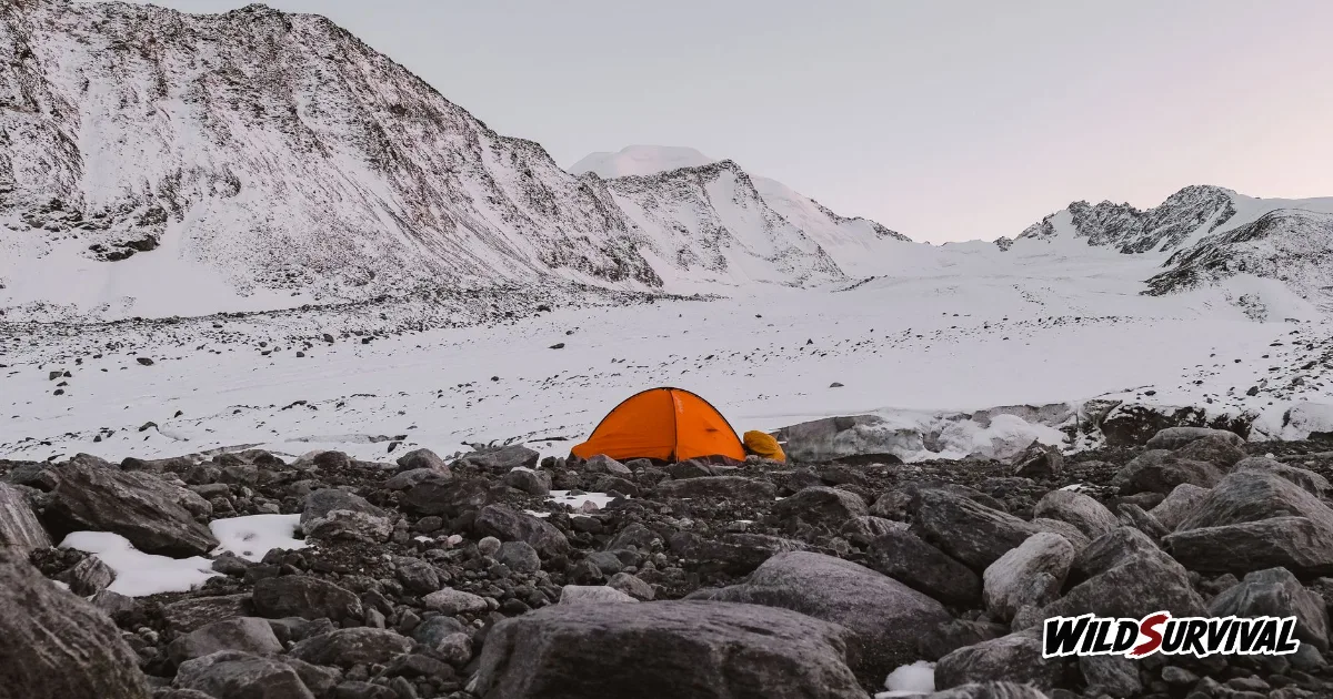 Leave No Trace wild camp with an orange tent pitched on rocky, snowy ground